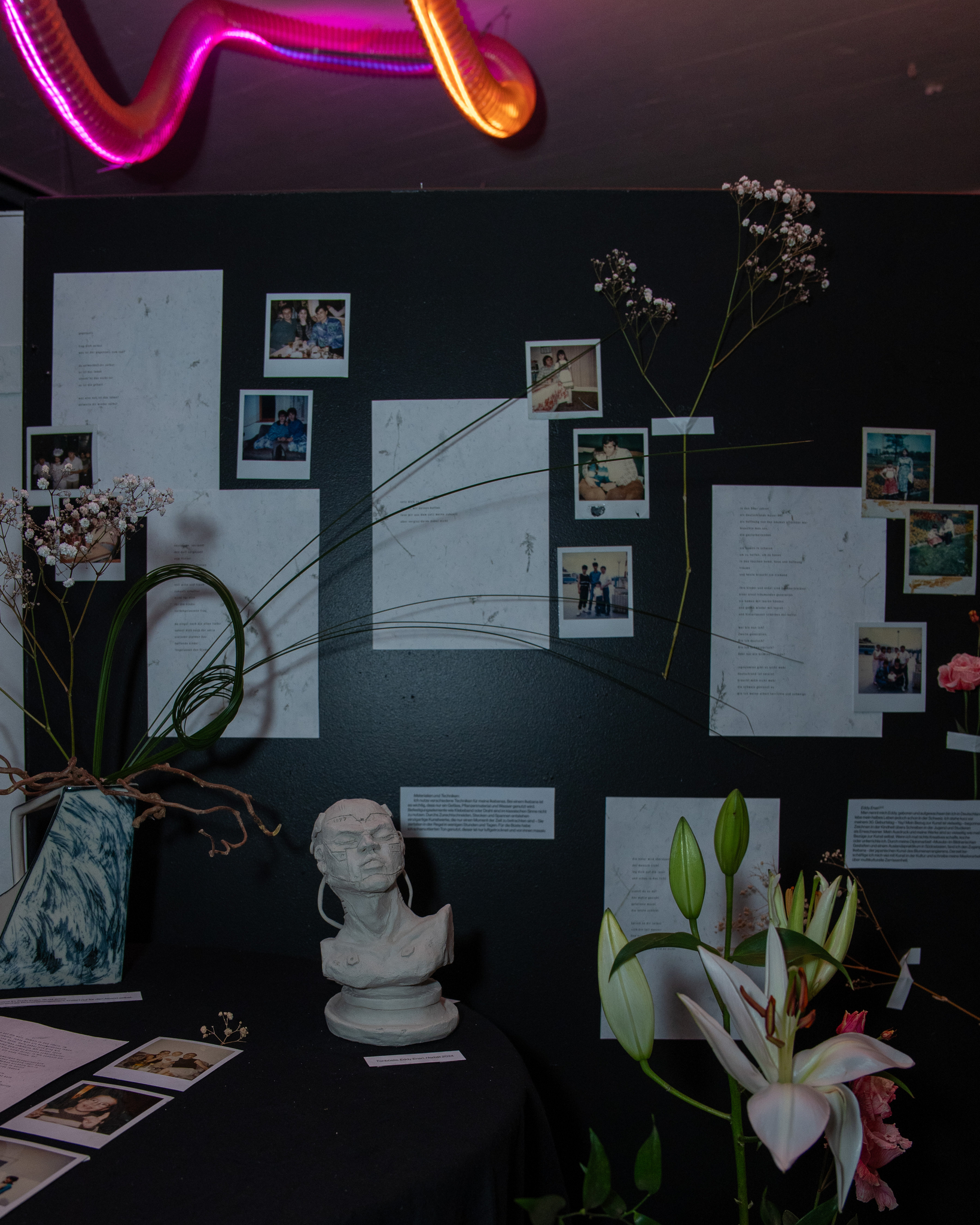 Polaroid-Installation mit Skulptur und Blumen